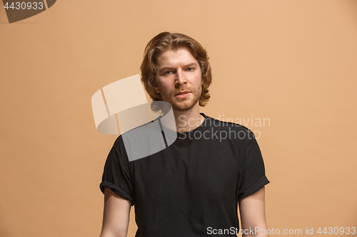 Image of The serious businessman standing and looking at camera against pastel background.