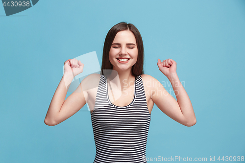 Image of The happy woman standing and smiling against blue background.