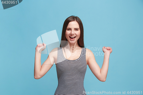 Image of The happy woman standing and smiling against blue background.