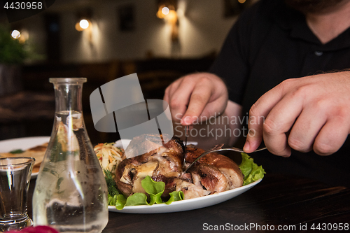 Image of Man eats tasty dish of pork shank