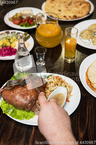 Image of Man eats tasty dish of pork shank