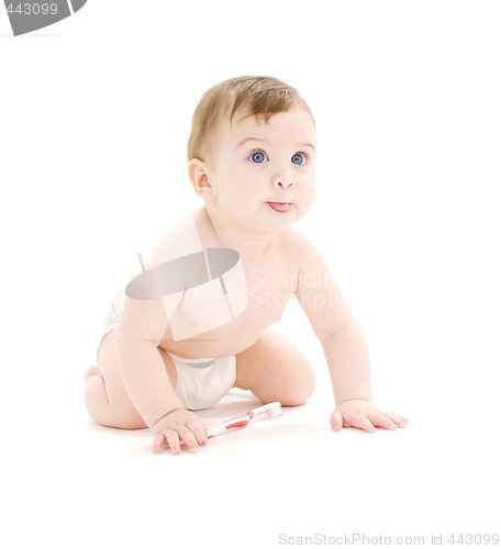 Image of baby boy in diaper with toothbrush sticking tongue out