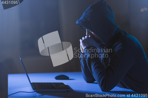 Image of hacker with laptop computer in dark room