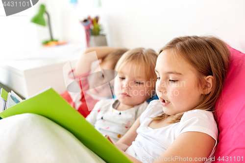 Image of little kids reading book in bed at home