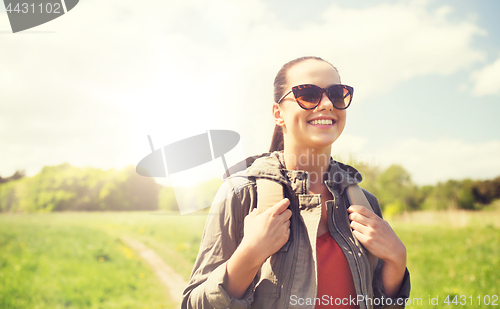 Image of happy young woman with backpack hiking outdoors