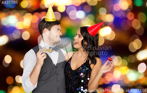 Image of happy couple with party blowers having fun