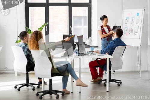 Image of woman showing tablet pc to creative team at office