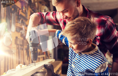 Image of father and son with drill working at workshop