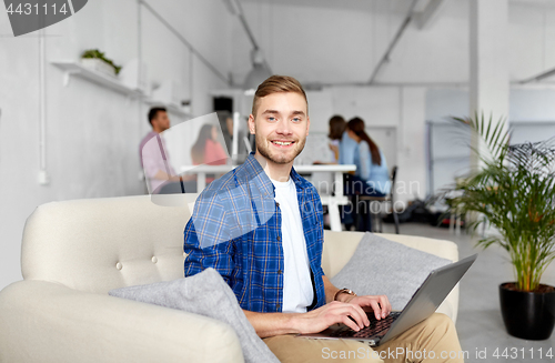 Image of smiling man with laptop working at office