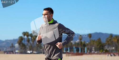 Image of happy young man running over venice beach