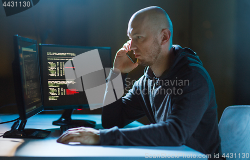 Image of hacker with program on computer calling on cell