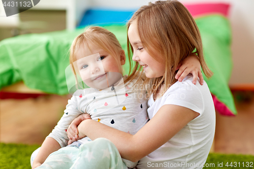 Image of happy little girls or sisters hugging at home