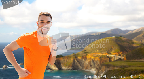 Image of smiling young man running at summer seaside