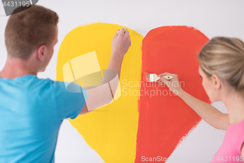 Image of couple are painting a heart on the wall