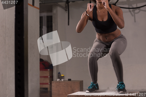 Image of black woman is performing box jumps at gym