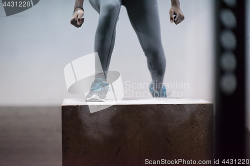 Image of black woman is performing box jumps at gym