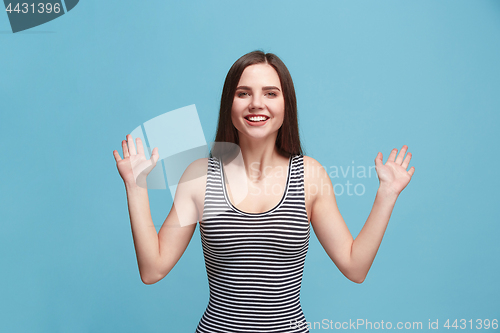 Image of The happy woman standing and smiling against blue background.