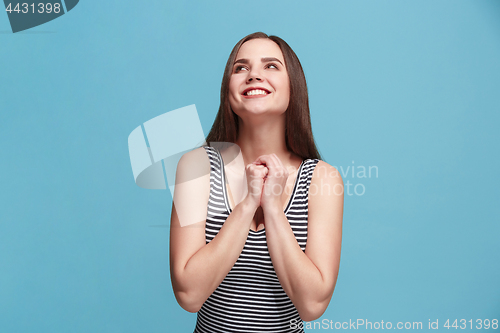 Image of The happy woman standing and smiling against blue background.