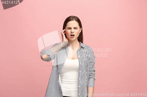 Image of The Ear ache. The sad woman with headache or pain on a pink studio background.