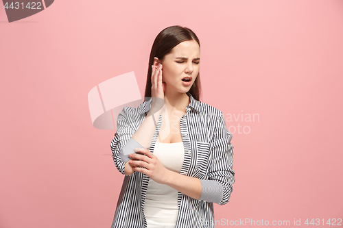 Image of The Ear ache. The sad woman with headache or pain on a pink studio background.