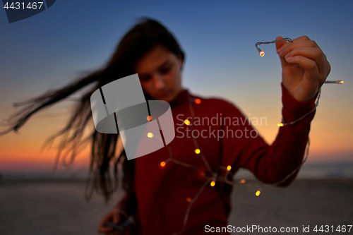 Image of Teen girl with lights on beach
