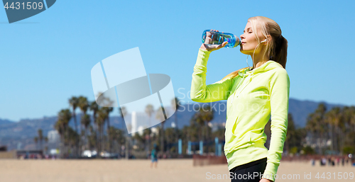 Image of woman drinking water after doing sports outdoors