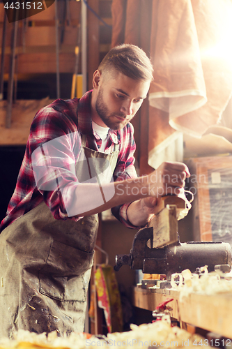 Image of carpenter working with plane and wood at workshop