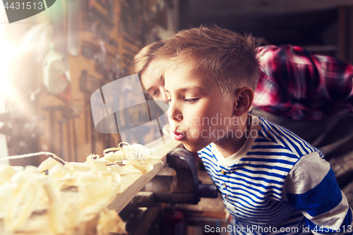 Image of father and little son with wood plank at workshop