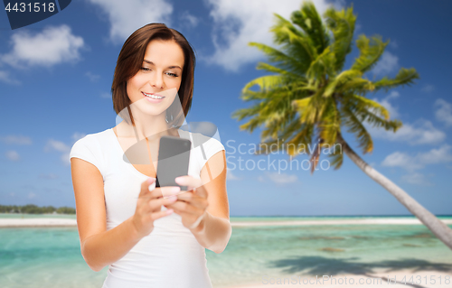 Image of woman taking selfie by smartphone on beach