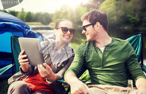 Image of happy couple with tablet pc at camping tent