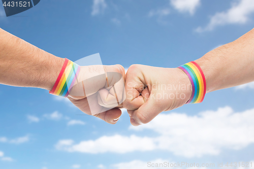 Image of hands with gay pride wristbands make fist bump
