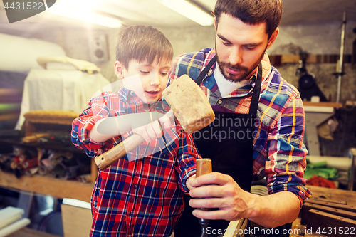 Image of father and son with chisel working at workshop