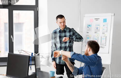 Image of man showing smart watch to creative team at office