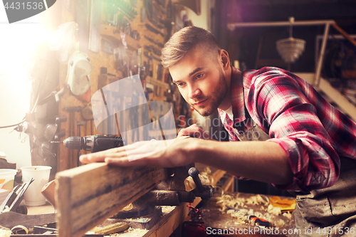 Image of carpenter working with wood plank at workshop