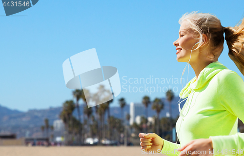 Image of woman with earphones running over venice beach