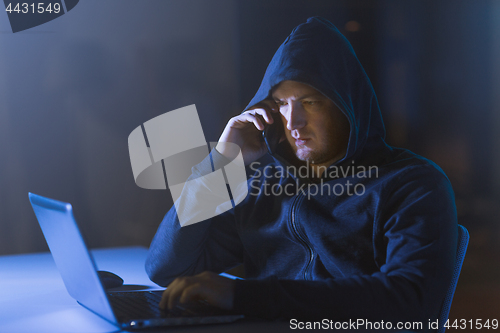 Image of hacker with laptop calling on cellphone