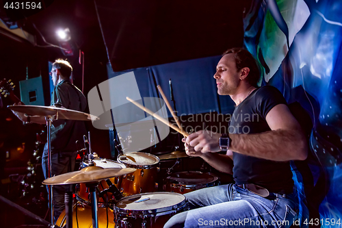 Image of Drummer playing on drum set on stage.