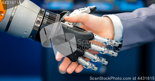 Image of Hand of a businessman shaking hands with a droid robot. The conc