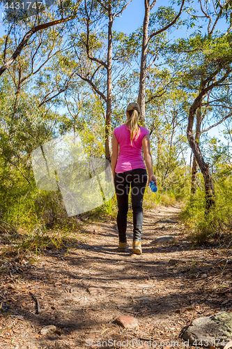 Image of Female walking along a bush track among nature