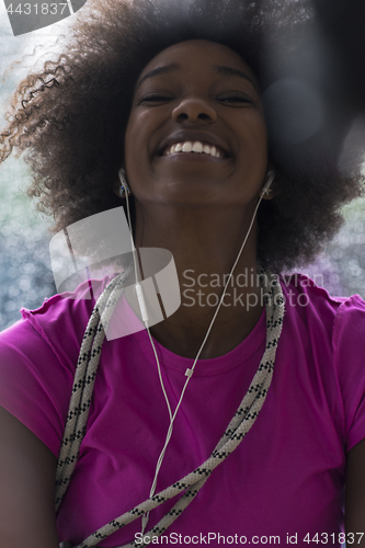 Image of portrait of young afro american woman in gym while listening mus