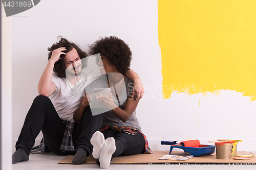 Image of young multiethnic couple relaxing after painting