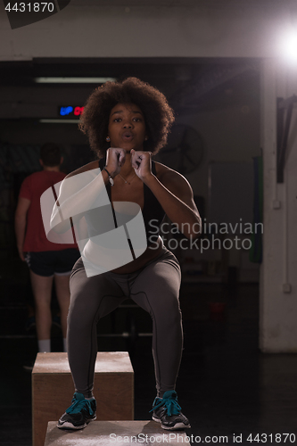 Image of black female athlete is performing box jumps at gym