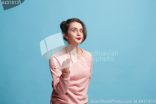 Image of Beautiful female half-length portrait isolated on blue studio backgroud. The young emotional surprised woman