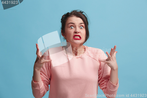 Image of Portrait of an angry woman looking at camera isolated on a blue background