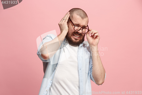 Image of The Ear ache. The sad man with headache or pain on a pink studio background.