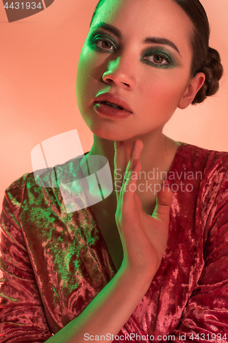 Image of High Fashion model woman in colorful bright lights posing in studio,