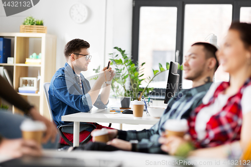 Image of creative man with smartphone at office