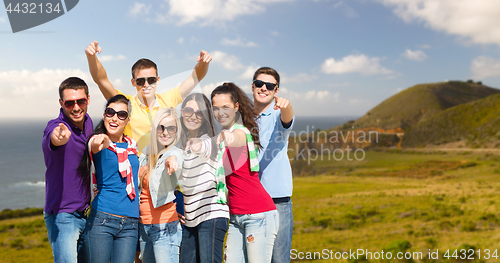 Image of happy friends pointing at you over big sur coast