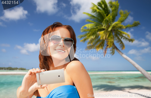 Image of woman taking selfie by smartphone on beach