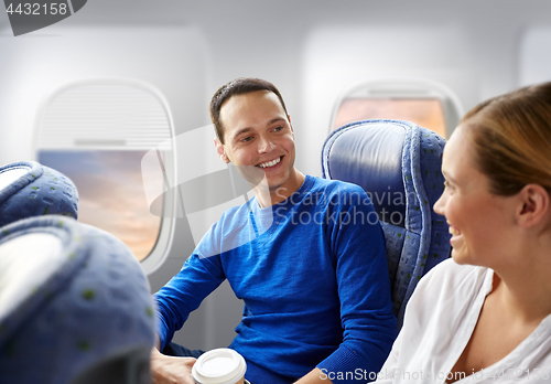 Image of happy passengers with coffee talking in plane